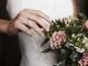 Bride wearing wedding ring near flowers